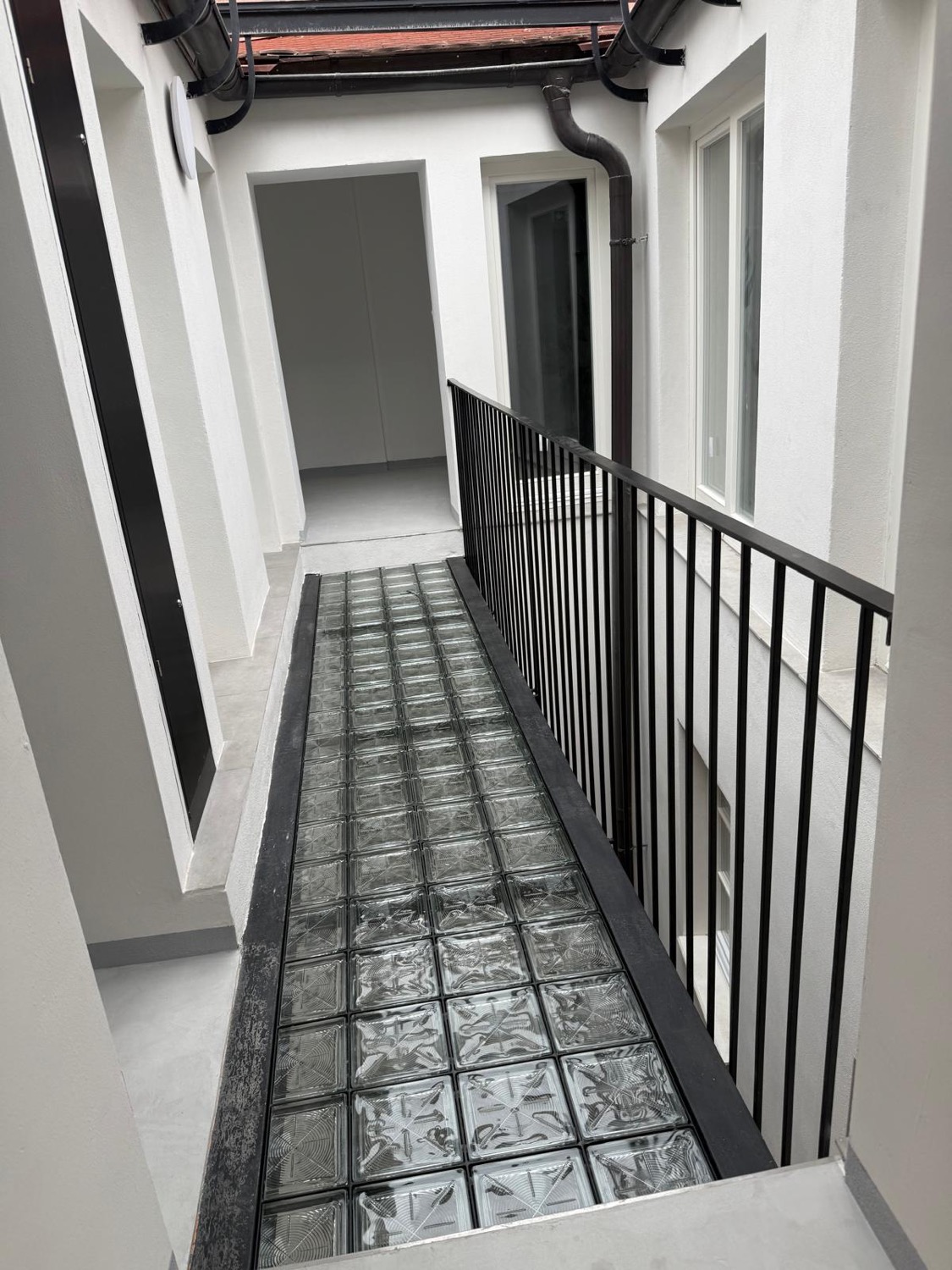 A glass-paved walkway over a light well with a balustrade and tall windows